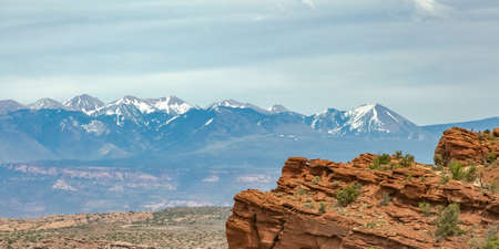Cliff with snow capped La Sal Mountain in Moab UTの写真素材