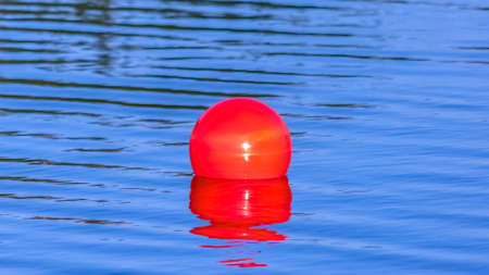 Bright red ball floating on the calm Oquirrh Lakeの写真素材