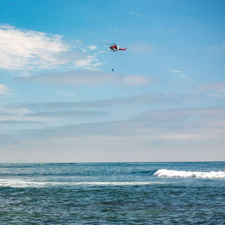 Helicopter with hanging person above La Jolla seaの写真素材