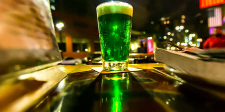 Glass with bright green liquid on a table at nightの写真素材