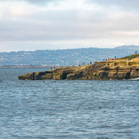 Steep cliff with people and vast ocean in La Jolla