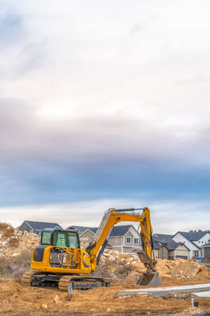 Excavator against homes and sky in Utah Valleyの写真素材