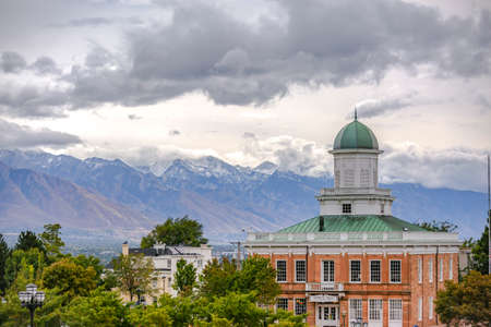 Buildings and snow capped mountain under cloudsの写真素材