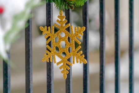 Golden snowflake on garland against dark railingの写真素材
