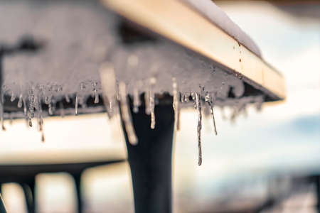 Icicles formed under a table with snow on topの写真素材