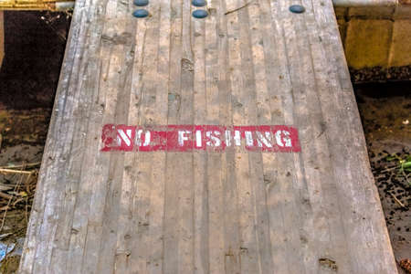No Fishing sign on wooden deck over murky waterの写真素材