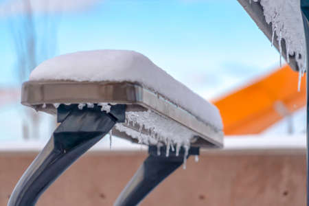 Icicles under a bench topped with a layer of snowの写真素材
