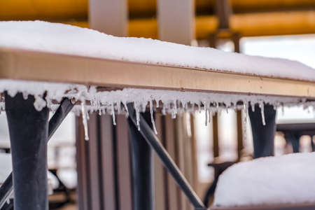 Icicles under an outdoor table covered with snowの写真素材