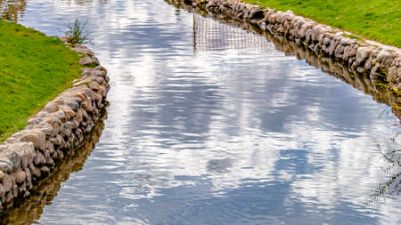 Shiny stream with rocky bank amid a grassy terrainの写真素材