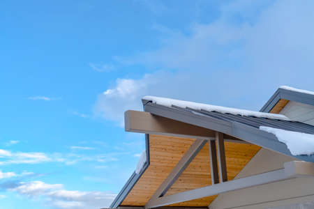 Snow covered roof against blue sky with cloudsの写真素材