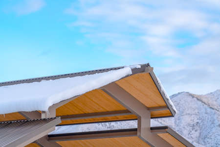 Snowy roof against snow covered mountain and skyの写真素材