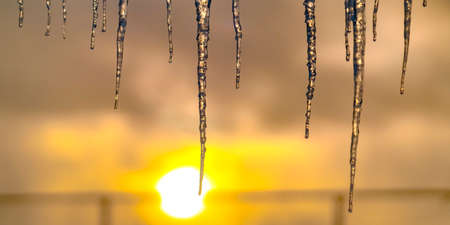 Sparkling icicles against a bright golden sunsetの写真素材
