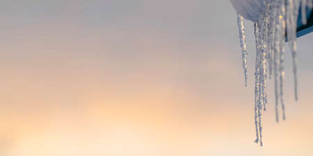 Sparkling icicles on a roof with sky backgroundの写真素材