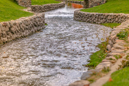 Sparkling stream curving through a trimmed lawnの写真素材