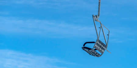 Chair lift against blue sky in Park City Utah. Close up view of an empty chair lift with bright blue sky in the background. Ski lift on a ski resort in Park City, Utah on a beautiful winter day.の写真素材