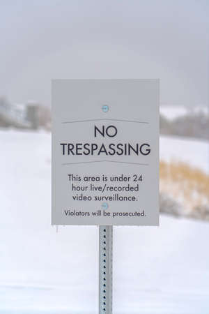 No Trespassing sign against a snowy landscape. No Trespassing sign on a snow covered property in Daybreak, Utah. The sign prohibits people from trespassing into the property under video surveillance.の写真素材
