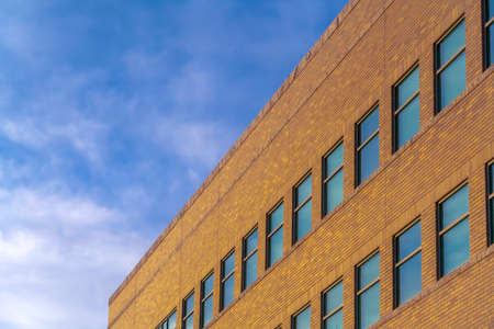 Modern building exterior under bright blue sky. Modern brick building exterior under vibrant blue...