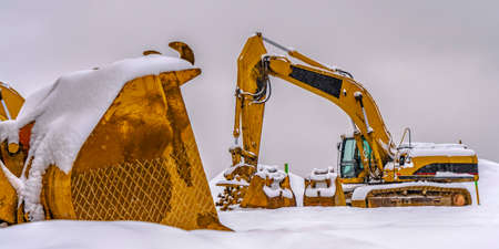 A bright yellow construction vehicles against snowの写真素材