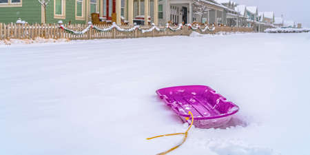 Puprle sled on snow with homes in the backgroundの写真素材