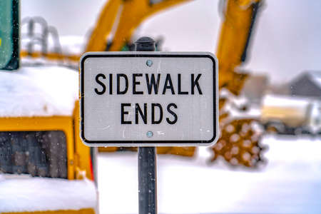 Sidewalk Ends sign against excavator and snowの写真素材