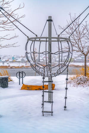Climbing frame against lake and homes in winterの写真素材