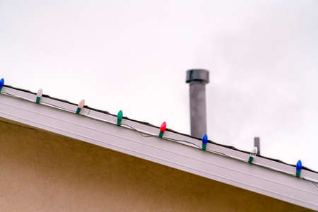 Roof of home lined with colorful Christmas lightsの写真素材
