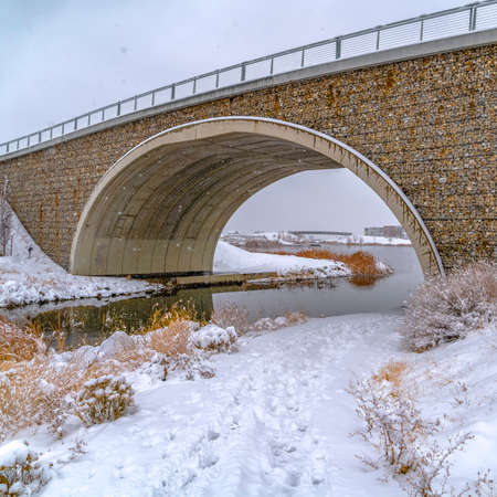 Arched bridge over lake and trail in winterの写真素材