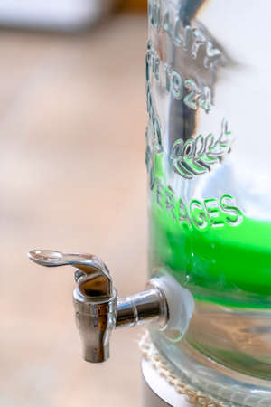 Close up of a glass beverage dispenser with faucet
