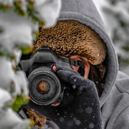 Photographer working during winter in Daybreak. A photographer working on a cold winter day in Daybreak, Utah. The person is taking a picture of a tree covered with fresh sharp white snow.の写真素材
