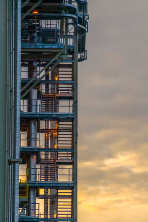 Staircase of Power Plant in Utah Valley at sunset. Metal staircase with lights at a Power Plant in Utah Valley. A cloud-filled sky with the glow of sunset can be seen behind the flight of stairs.の写真素材