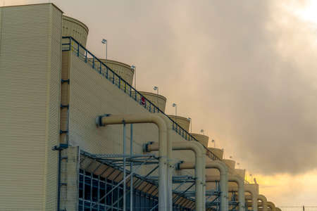 Thick gray steam from a Power Plant in Utah Valley. Building at a Power Plant in Utah Valley emitting thick gray steam into the sky. Large pipes are connected to the building with ridges on the wall.の写真素材