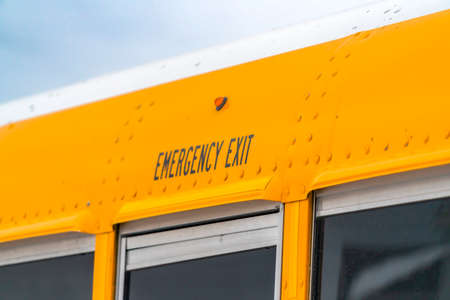 Close up of the exterior of a yellow school bus with an Emergency Exit sign
