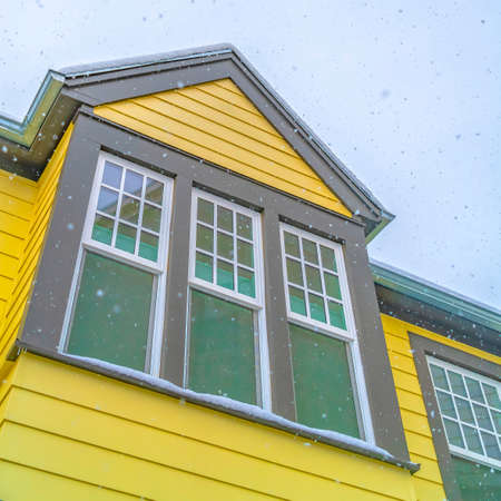 Home in Daybreak Utah with yellow wall and reflective glass windows against skyの写真素材