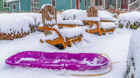 Panorama Purple sled and wooden chairs surrounded by snow during winter in Daybreak