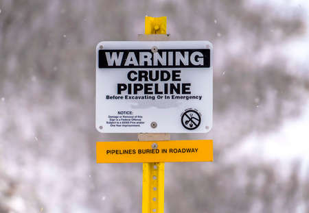 Close up of a Warning sign on an area with crude pipeline viewed in winterの写真素材