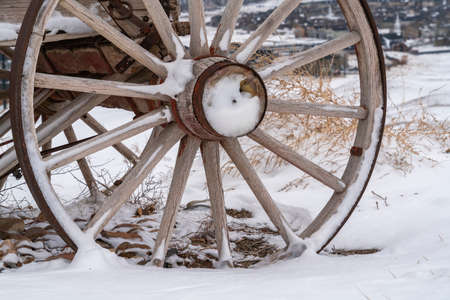 Close up of the wooden wheel of an old wagon against a snowy terrain in winterの写真素材