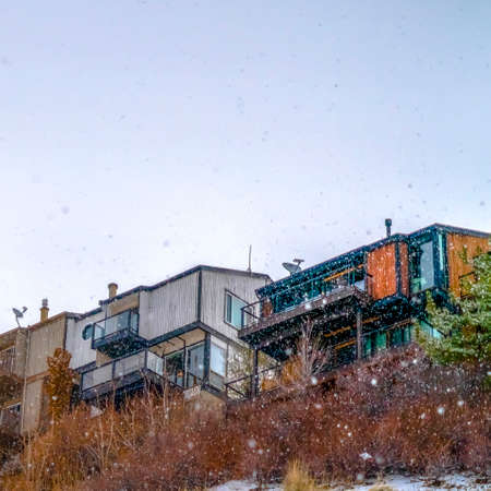 Square Homes on snowy mountain against bright sky