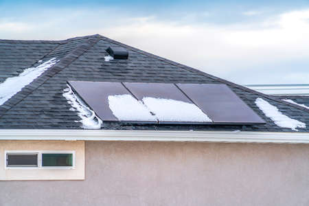 Solar panels on the roof of a home against blue sky with cloudsの写真素材