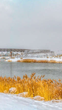 Clear Vertical A gleaming lake with grasses lining the shore in Daybreak Utah in winter. The bridge...