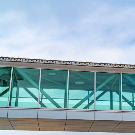 Square Looking up at an empty skybridge with a cloudy blue sky in the background. A mountain can also be viewed from the inside of the skywalk through the clear glass walls.の写真素材