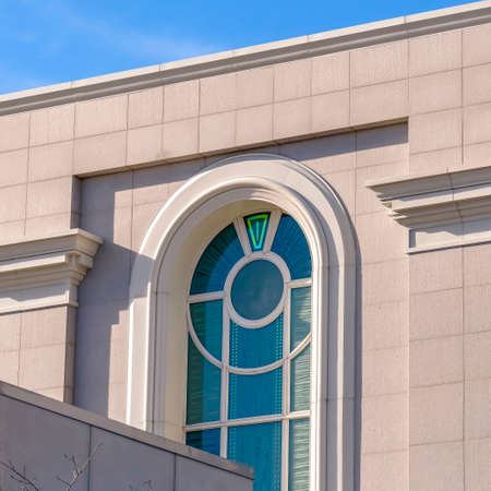 Square Building exterior with vibrant blue sky background on a sunny day. The sunlit white building...
