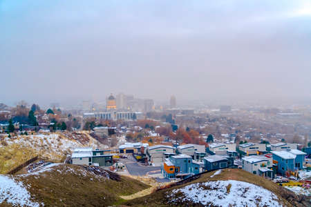 Salt Lake City downtown against cloudy sky viewed from a snowy hill in winter. The historic Utah Stae Capital Building towers majestically over the cityscape.の写真素材