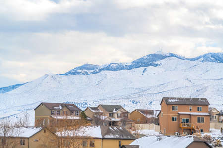 Town built on a mountain blanketed with fresh snow against cloud filled sky. The color of the houses...