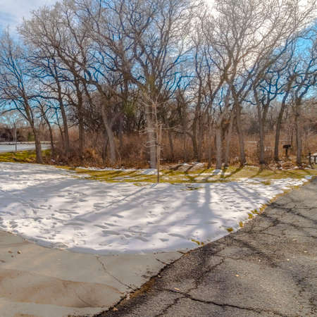 Clear Square Table and benches at a snowy picnic area near a lake on a sunny winter day. A view of snow capped mountain and vast blue sky can be seen beyond the icy lake.の写真素材