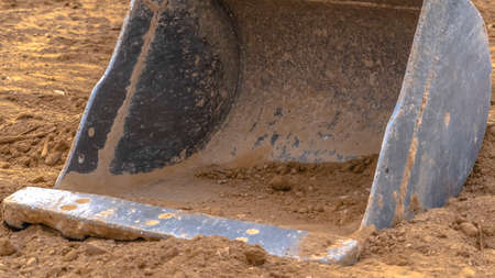 Panorama Close up of the dirty metal bucket of an excavator viewed on a sunny day. The bucket is on...