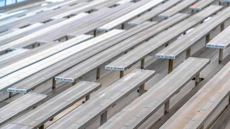 Clear Panorama Close up of tiered rows of benches at a sports field viewed on a sunny day. Seating numbers can be seen on the surface of the raised bleachers.の写真素材