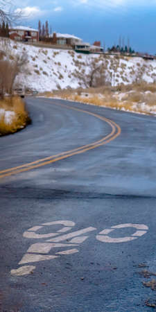 Vertical Bicycle lane sign painted on a winter road in Utahの写真素材