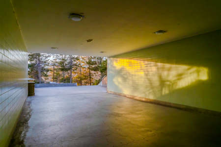 Passageway underneath a building with view of lush trees and sunny outdoors