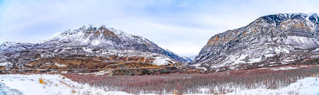 Panoramic view of an immense mountain dusted with snow against a cloudy sky
