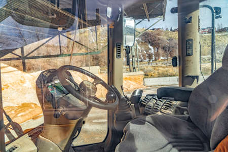 Construction vehicle cab interior with hill and sky in the sunny background